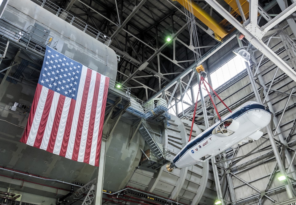 TTR installation into the wind tunnel: hoisting the rig from the NFAC High Bay. The test section is behind the flag. Photo March 2017.